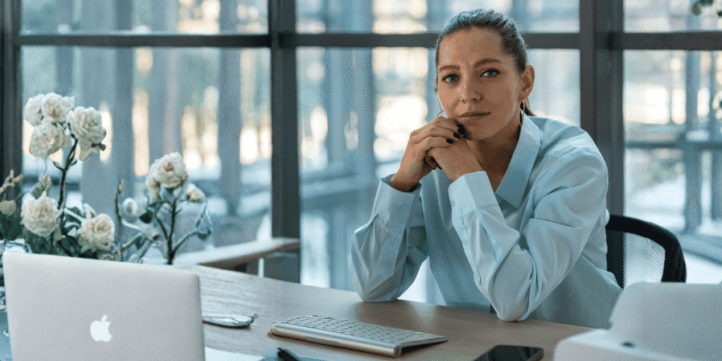 #19 - NR1 atualizada como implementar sem comprometer a rotina da empresa Profissional sentada à mesa no ambiente de trabalho - NR1 atualizada - Qualitá Mais - banco de imagens